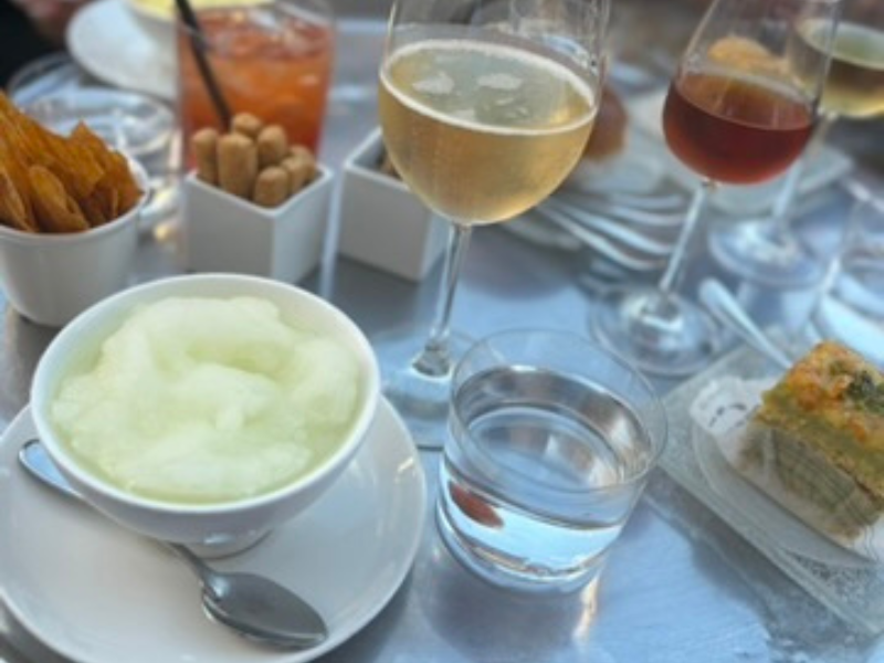 An assortment of Sicilian treats at Caffè Sicilia in Noto, including granita, wine, and savory snacks on an outdoor table.