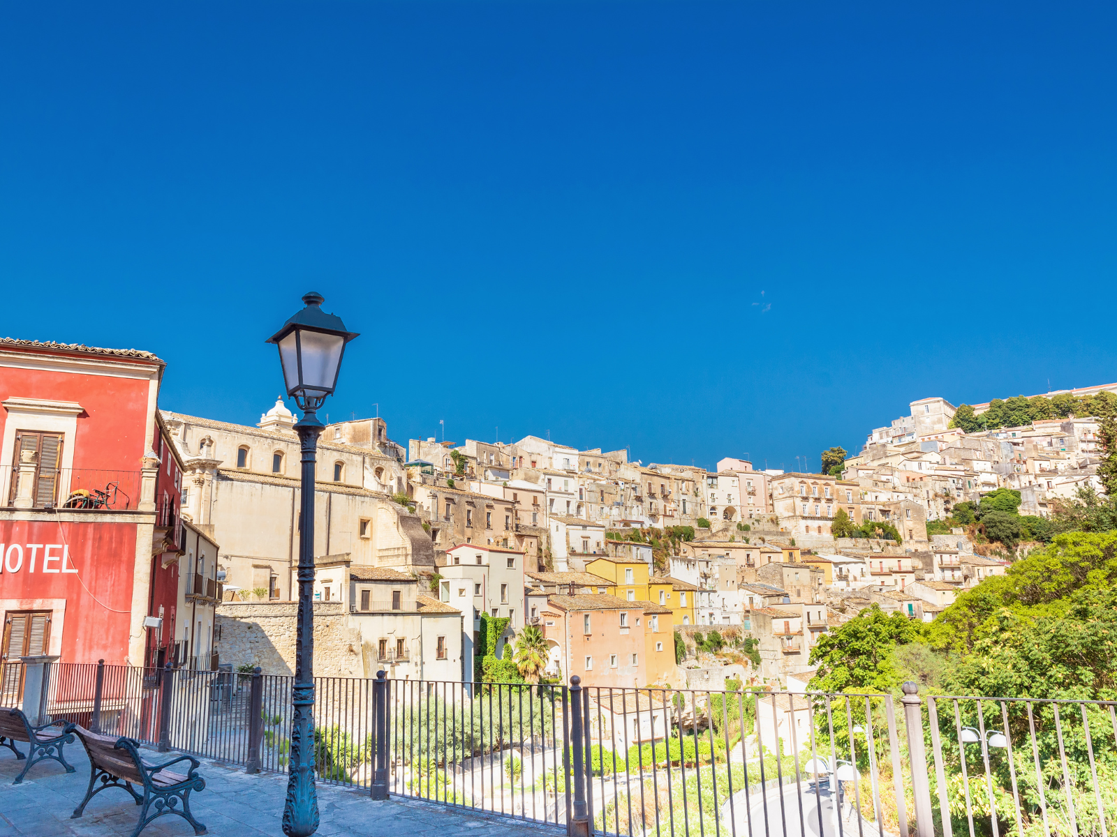 View of the historic hilltop town of Ragusa Ibla with colorful buildings under a clear blue sky.